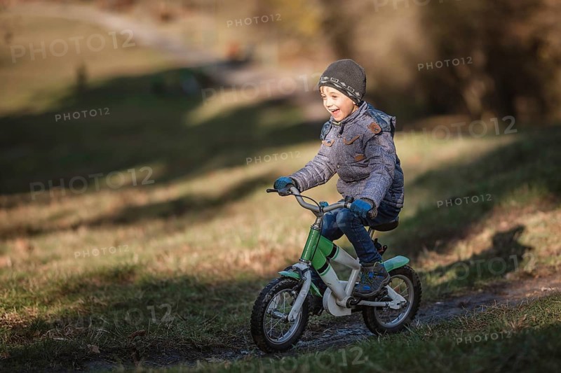 Six years old boy rides bicycle from the hill in the park