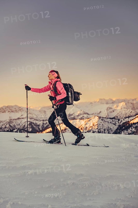 A woman's ski tour at sunrise on the Tegelberg in the Allgäu in the Ammergebirge, Bavaria, Germany