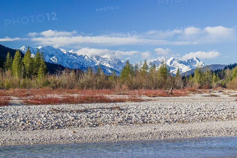 Isar valley nature conservancy area on an early sunny morning. The wild Isar river flows through its gravel bed past driftwood and entrained trees and bushes