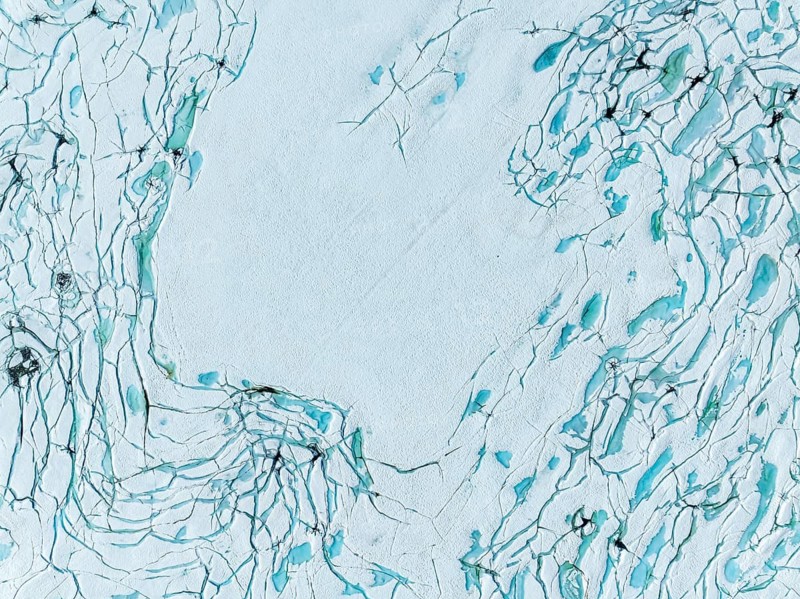 Aerial view of frozen lake Prestesteinsvatnet, melting snow creates small blue pools on the frozen surface, mountain crossing Sognefjellsvegen, Sognefjell, Norway