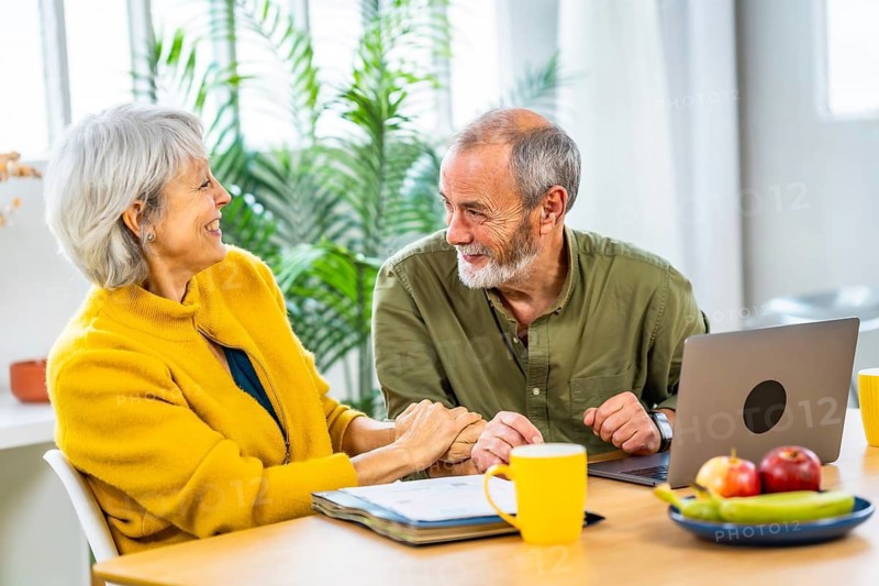 Senior woman celebrating good news while doing the household accounting with her husband sitting on the living room using laptop