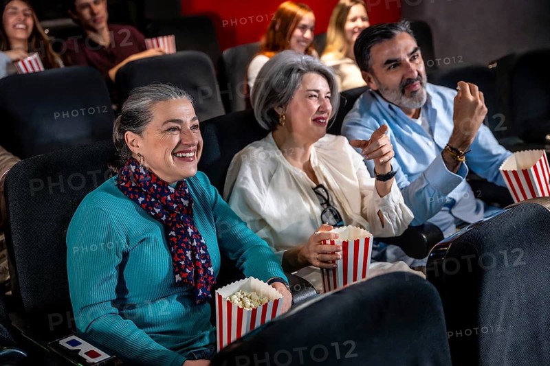 Laughter fills the air as friends and family enjoy popcorn while watching an exciting movie in a cozy cinema auditorium
