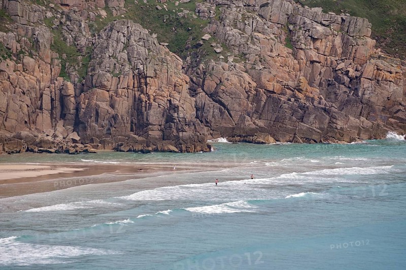 Näherer Blick auf eine felsige Küste mit kleinen Wellen am Strand, Porthcurno, St Levan, Cornwall, Großbritannien