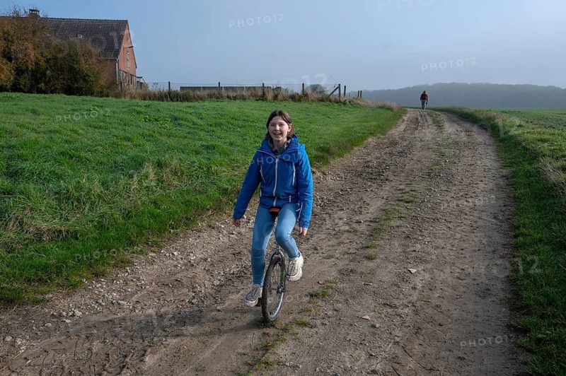 Laughing young girl, 10 years old, riding a unicycle on a dirt track, Mecklenburg-Vorpommern, Germany