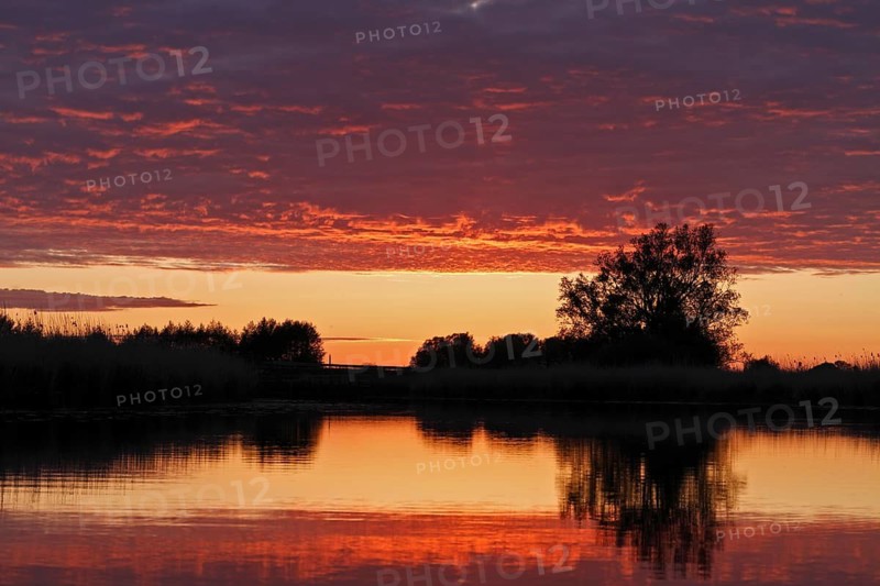 Clouds in the sunset with reflection on the river Trebel, Naturpark Flusslandschaft Peenetal, Mecklenburg-Western Pomerania, Germany