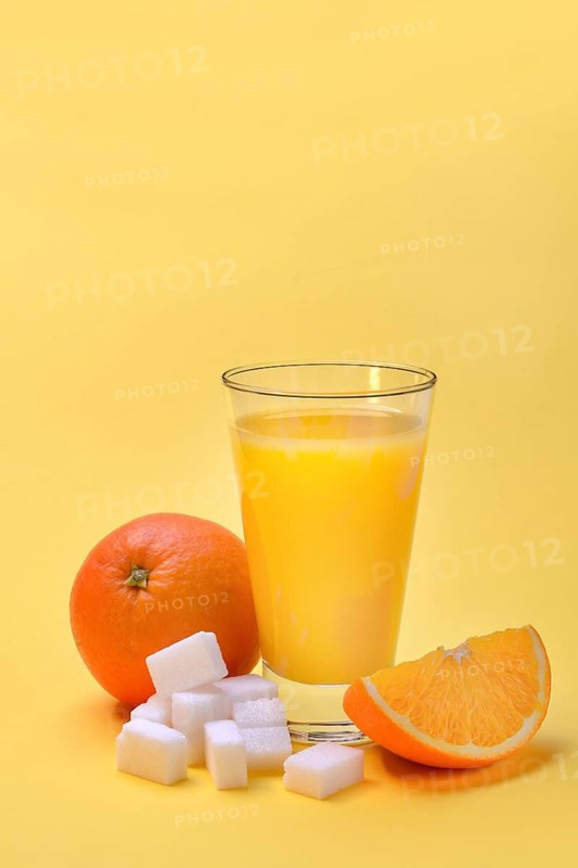 Orange juice in a drinking glass, half an orange and sugar cubes