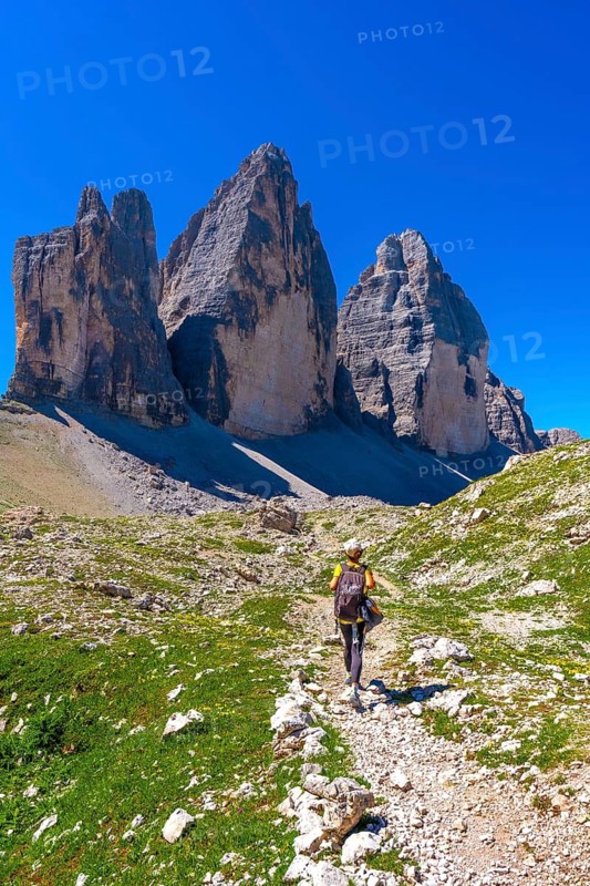 Hiker walking on a mountain path near tre cime di lavaredo in the dolomites on a sunny summer day