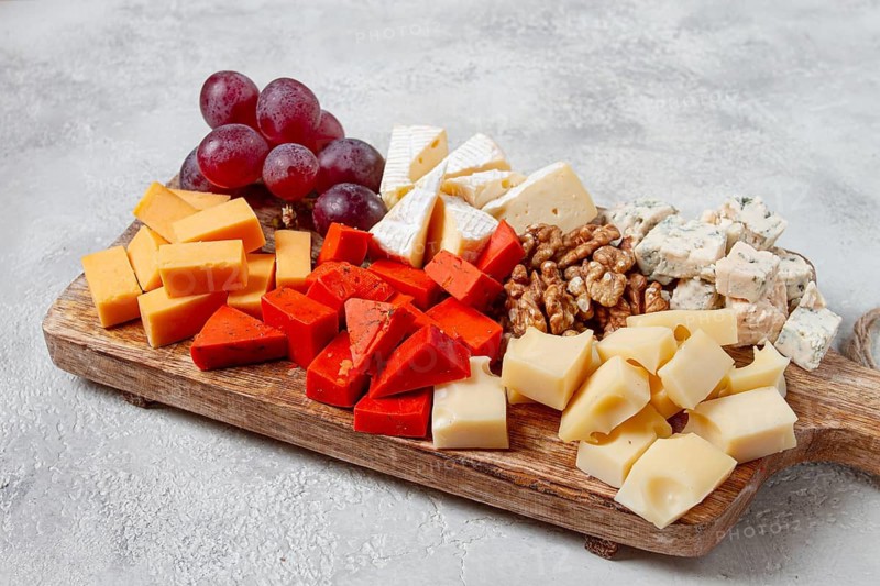 Assorted cheese on a wooden board, with grapes and walnuts, appetizer, no people