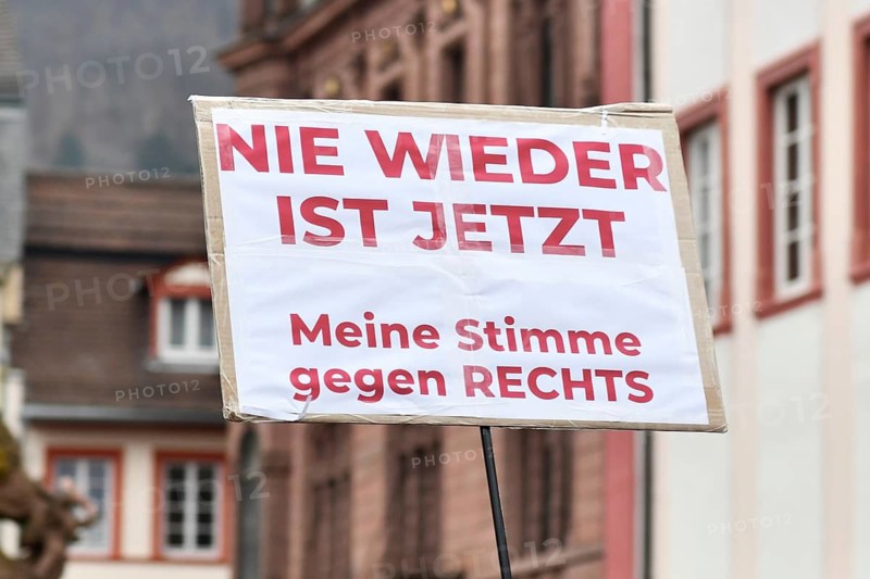 Heidelberg, Germany - February 12th 2025: Person holding up sign with text 'Never again is now' in crowd at protest against far-right