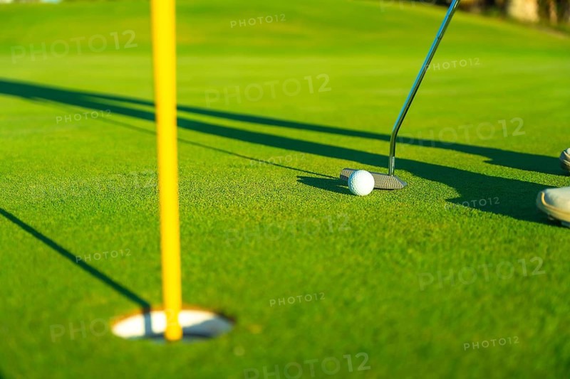 Close-up of golf ball and club near cup