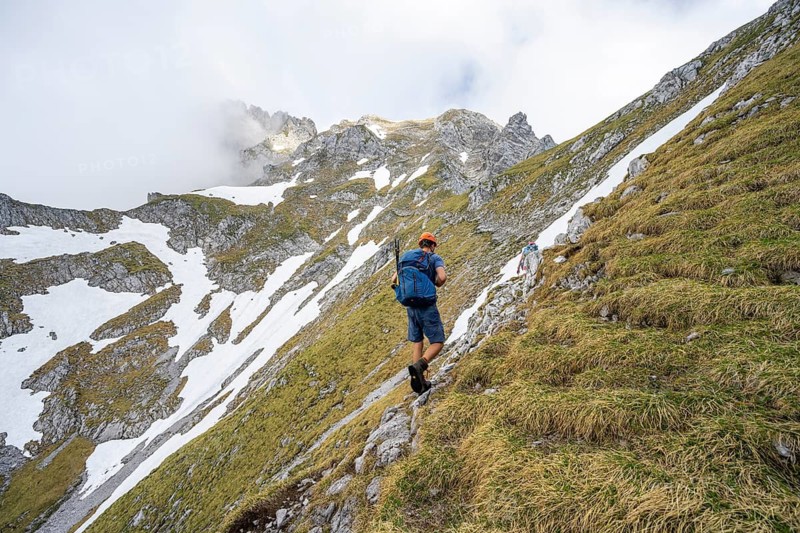 Mountaineer with helmet on a narrow hiking trail, ascent to the Ackerlspitze, clouds moving around the mountains, Wilder Kaiser, Kaiser Mountains, Tyrol, Austria