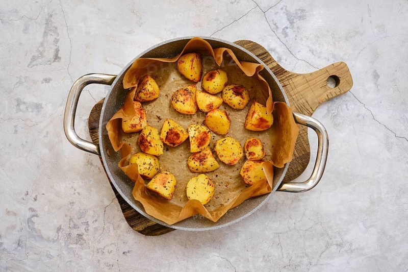 Golden brown roasted potatoes are beautifully arranged in a serving platter lined with parchment paper