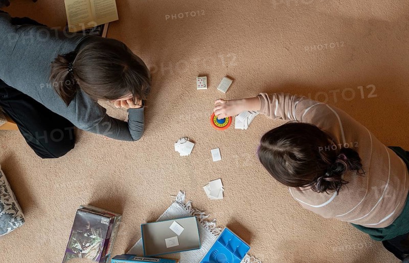Two young woman playing a parlour game on the carpet in the living room, Bavaria, Germany
