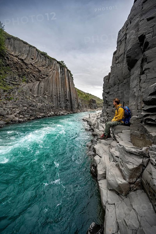 Tourist standing by the river in Stuðlagil Canyon, turquoise blue river between basalt columns, Egilsstadir, Iceland