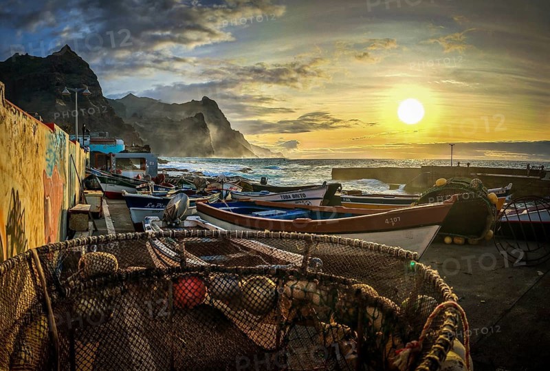Nets in the foreground, fishing boats at the harbor, graffiti on the wall and spectacular, dramatic sea views at sunset, Ponta do Sol, Santo Antao, Cabo Verde, Cape Verde, Cape Verde