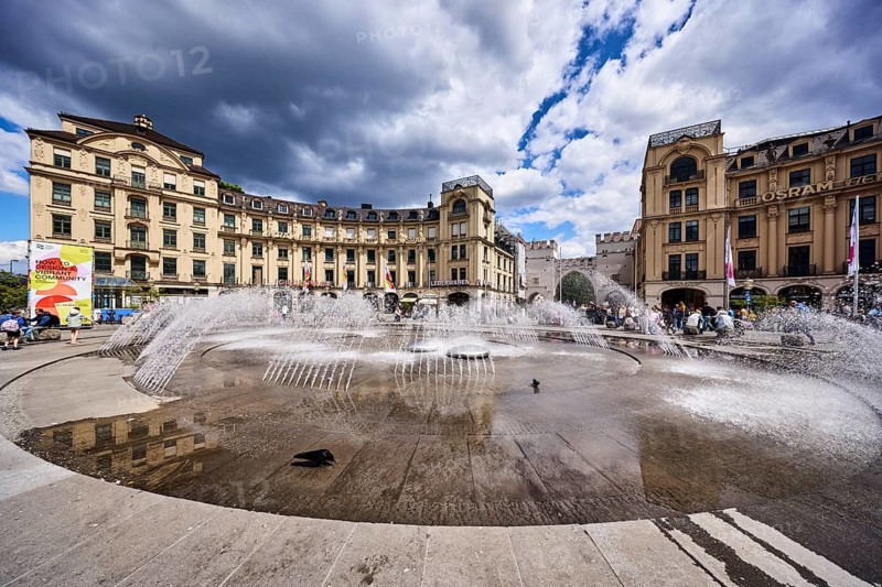 Fountain, general architecture, historic buildings, stachus roundel, neo-baroque style, architect Gabriel von Seidl, pedestrian zone, square, pedestrians as a secondary motif, blue sky, white and dark gray cumulus clouds, Stachus, Karlsplatz, Munich, state capital, district-free city, Bavaria, Germany