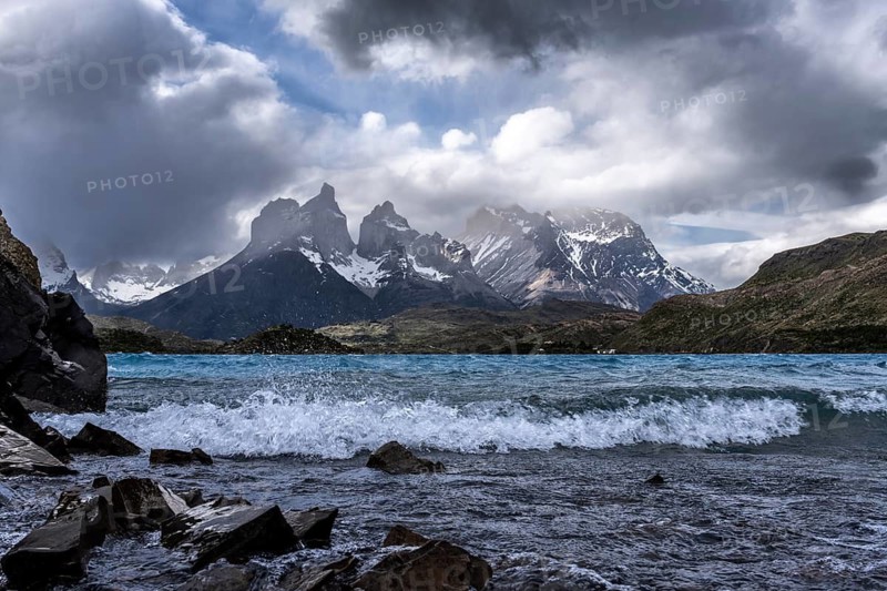 Cuernos del Paine with snow-capped peaks under dramatic cloud cover, storm-swept Lake Pehoé with breaking waves in the foreground, Torres del Paine National Park, Patagonia, Chile