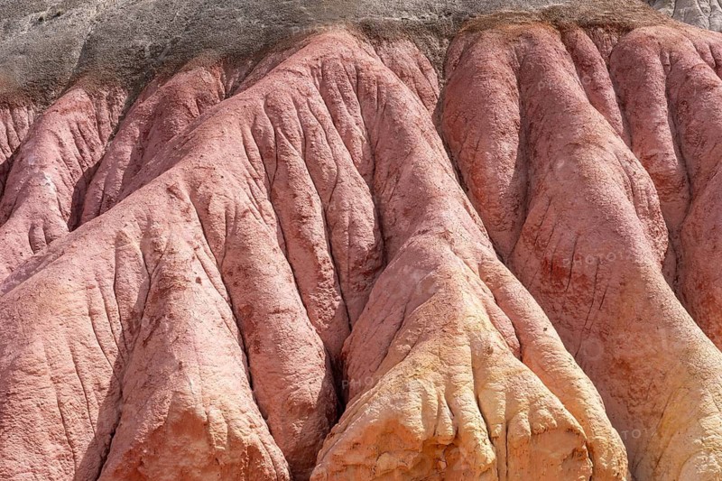 Eroded rock formation with pink, reddish and yellowish layers of color, washed out channels and ribs in clay-containing sedimentary rock, Santa Cruz province, Argentina