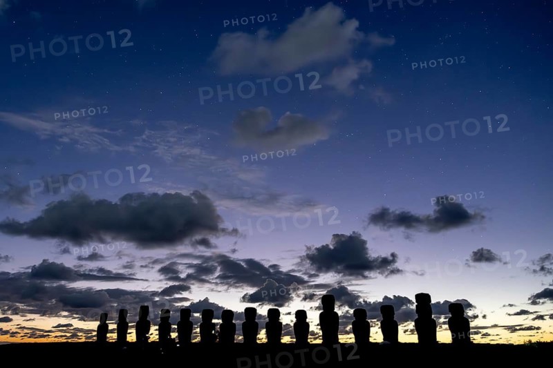 Silhouettes of the fifteen Moai statues of Ahu Tongariki against a starry sky and clouds at dawn, Easter Island, Chile