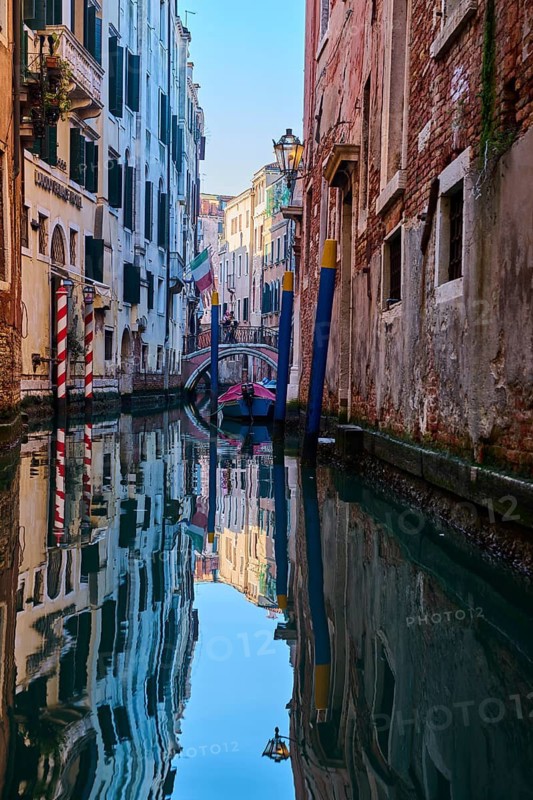 View from a gondola on a waterway in Venice going through the houses on a quiet and sunny morning in winter, Italy
