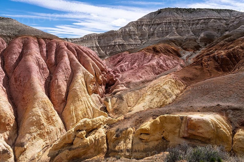 Colored sedimentary rock formations with red, yellow and gray layers, eroded Badlands landscape under blue sky, Santa Cruz province, Argentina