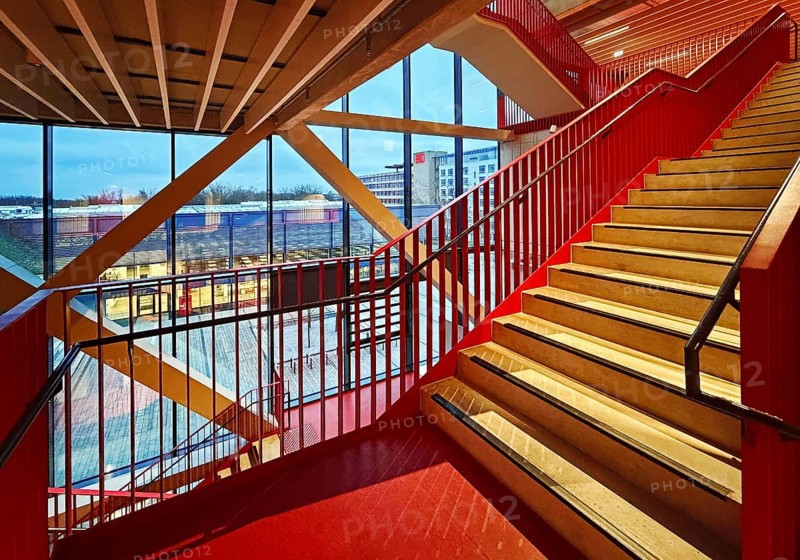 Staircase with signal red color scheme in seminar building H of Bochum University in the evening with a view of BlueBox Bochum, North Rhine-Westphalia, Germany