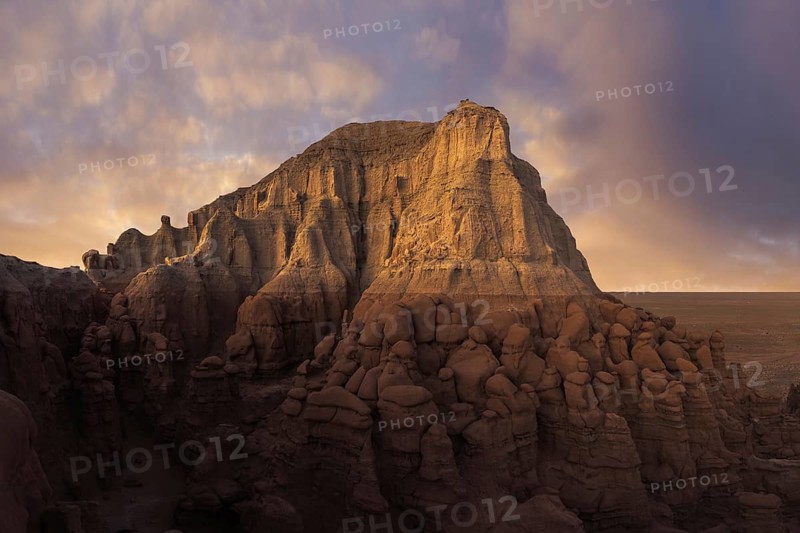 Captivating sandstone formations at Goblin Valley State Park bathed in warm, golden-hour light. The scenery highlights the unique erosion patterns and atmospheric skies in Utah