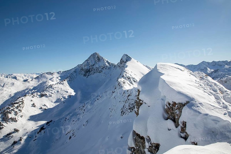 Explore untouched alpine peaks blanketed in fresh snow under a bright blue sky, ideal for adventurous freeride skiing enthusiasts seeking thrilling winter escapades