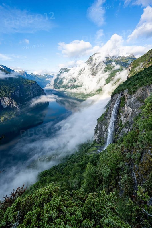Gjerdefossen waterfall, at Ørnesvingen viewpoint, atmospheric clouds over the fjord in the morning light, at Geirangerfjord, near Geiranger, Møre og Romsdal, Norway