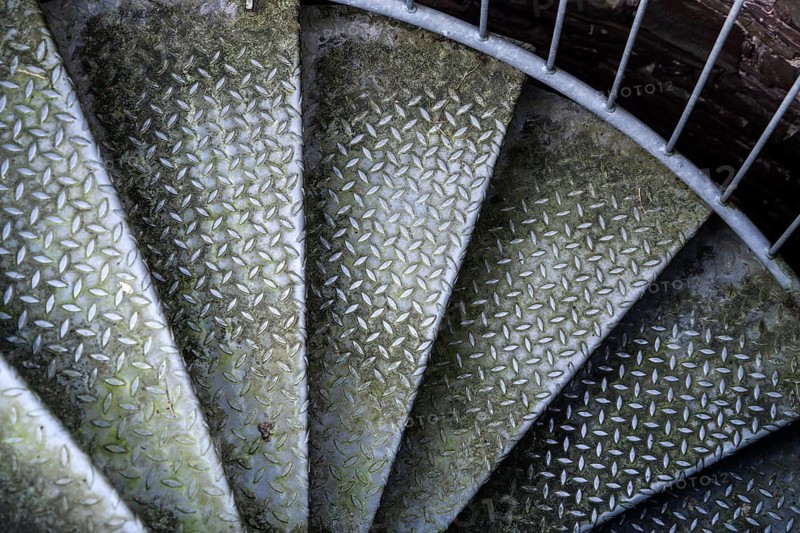 Steps of old metal spiral staircase disappear in darkness