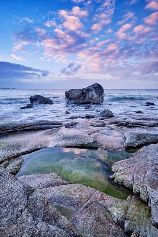 Rocks on beach of fjord of Norwegian sea in winteron sunset. Utakliev beach, Lofoten islands, Norway