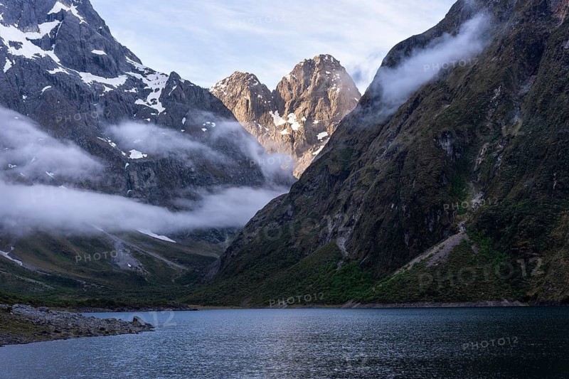 Landscape in New Zealand with mountains and lake. Lake Marian in the evening with clouds coming in. Fiordland National Park, Southland Region, South Island, New Zealand