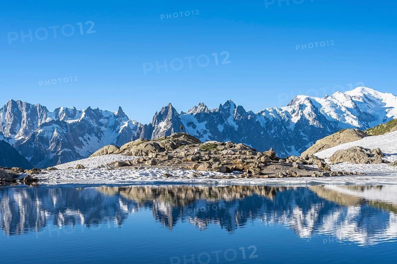 Young man in front of impressive mountain landscape in morning light, reflection in the Lac Blanc mountain lake, mountain summit, Aiguille Verte, Grandes Jorasses, Aiguille du Moine, Mont Blanc, Mont Blanc Massif, Chamonix-Mont-Blanc, Haute-Savoie, France