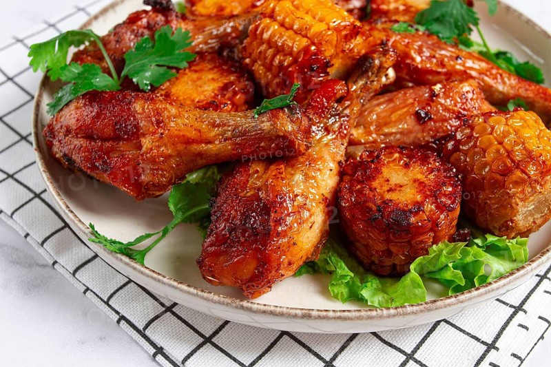 Fried chicken drumsticks, Mexican style, with corn, on a plate, close-up