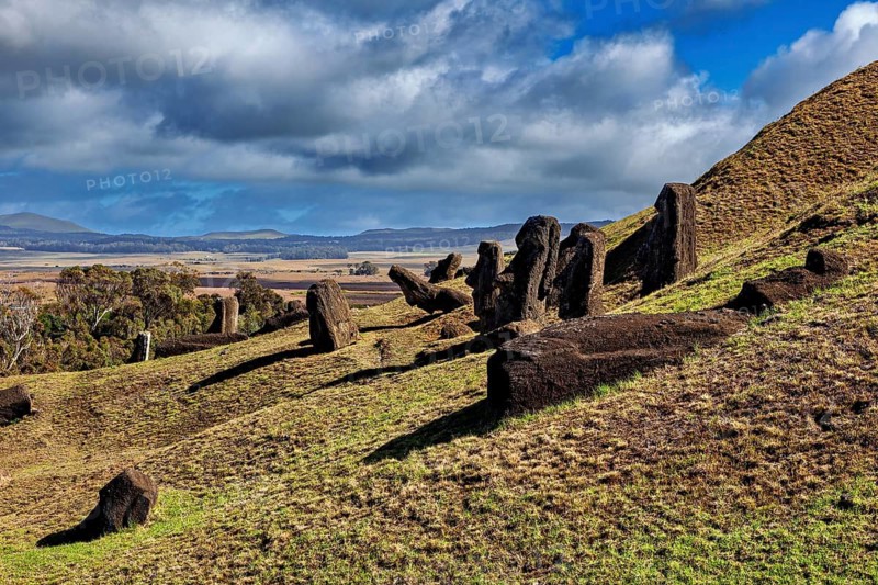 Lonely Moai statues stand leaning on a grassy hill under clouds, The Moai Statues on Easter Island in the Pacific Ocean