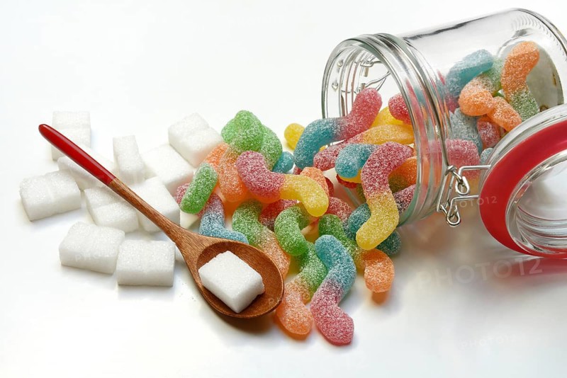 Lots of colorful jelly sweets in glass containers and sugar cubes, sugar consumption