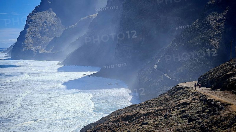 Dramatic coastline with steep cliffs and a misty path along the sea, spray, two hikers in the distance, hiking from Cruzinha to Ponta do Sol, hiking, Santo Antao, Cabo Verde, Cape Verde, Cape Verde