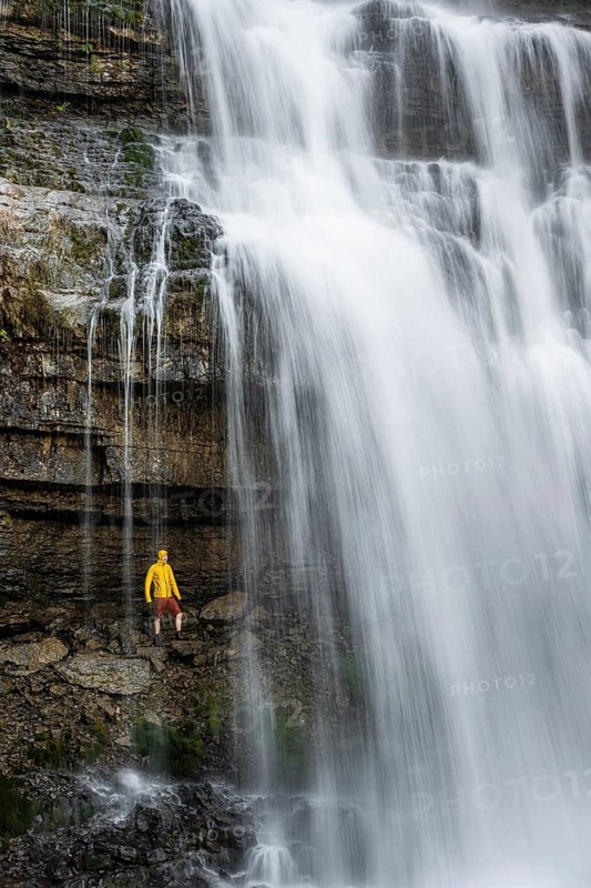 Adventure, Little hiker under large Cascata di Mezzo waterfall, long exposure, Vallesinella, Brenta, Trentino, Italy