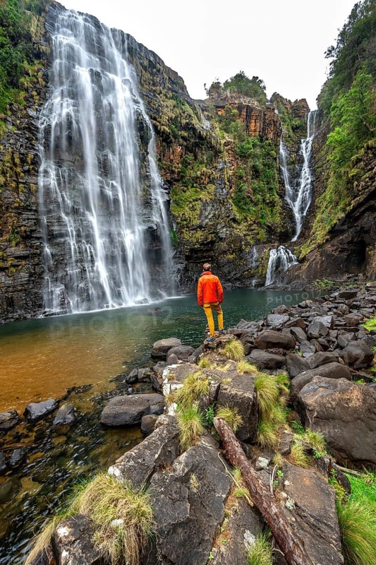 Young man standing in front of a waterfall, Lisbon Falls, long exposure, near Graskop, Mpumalanga, South Africa