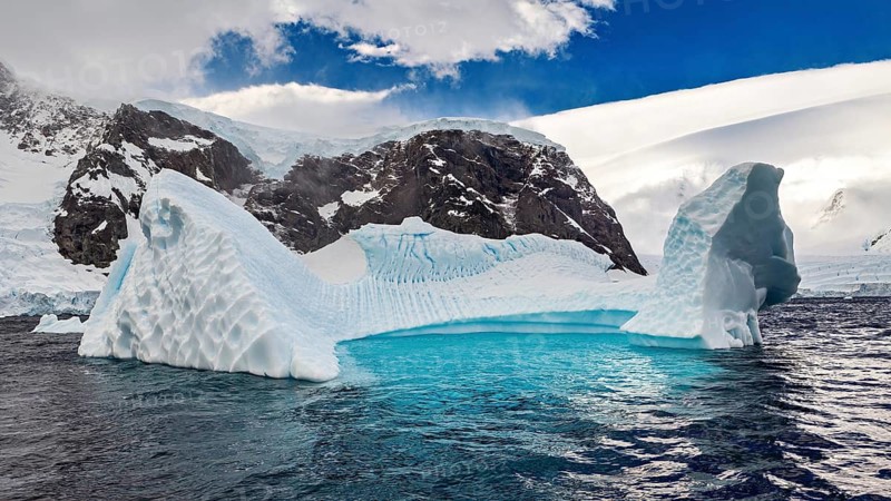 Frozen iceberg with arch-like structure details under a clear blue sky, icebergs in the landscape of the Southern Ocean in Antarctica