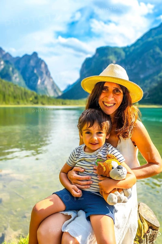 Happy mother and son are enjoying their summer vacation at lake dobbiaco with stunning mountain views in the dolomites