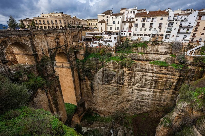 Dramatic wide angle view of the Puente Nuevo bridge, showing the massive stone structure spanning the deep El Tajo gorge in Ronda, Spain