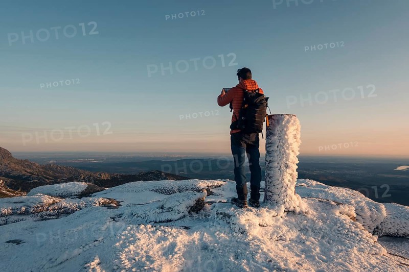A stunning snowy view at Siete Picos, part of the Guadarrama Mountains in Madrid. A hiker stands on the frosty summit, capturing the expansive winter landscape