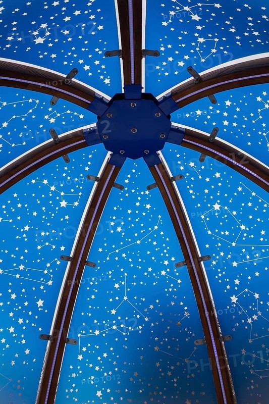 Close-up of backlit blue tinted plexiglass and curved wood panels canopy decorated with white starry vault theme motifs inside interactive cocoon rocking chair made by Olivier Landreville, Horizon Art Installation, Ile des Moulins, Old Terrebonne, Quebec, Canada