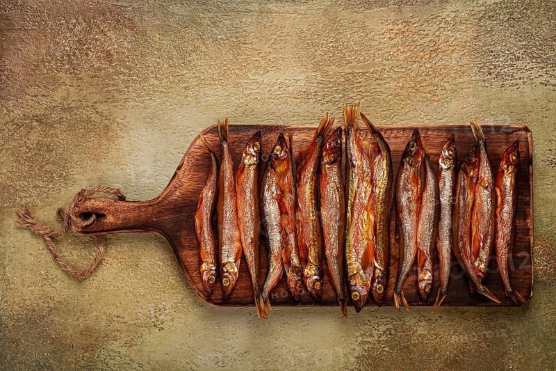 Cold smoked capelin, on a wooden chopping board, no people