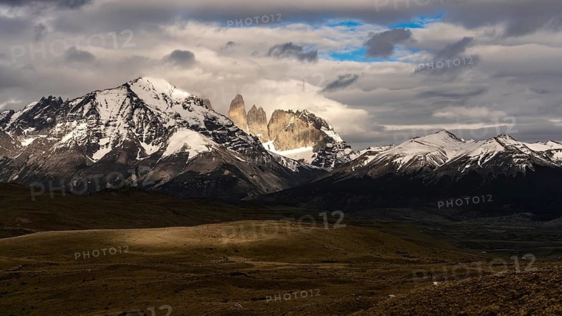 Torres del Paine granite peaks, snow-capped mountain peaks behind clouds, steppe landscape in the foreground, Torres del Paine National Park, Patagonia, Chile