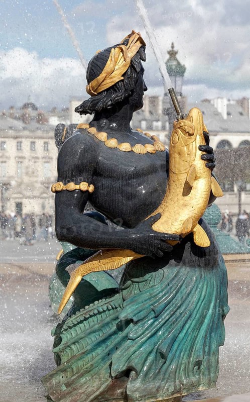 Water-breathing figure with fish at the Fontaine des Mers by Jacques Hittorff, cast iron fountain from 1840, Place de la Concorde, Paris, France