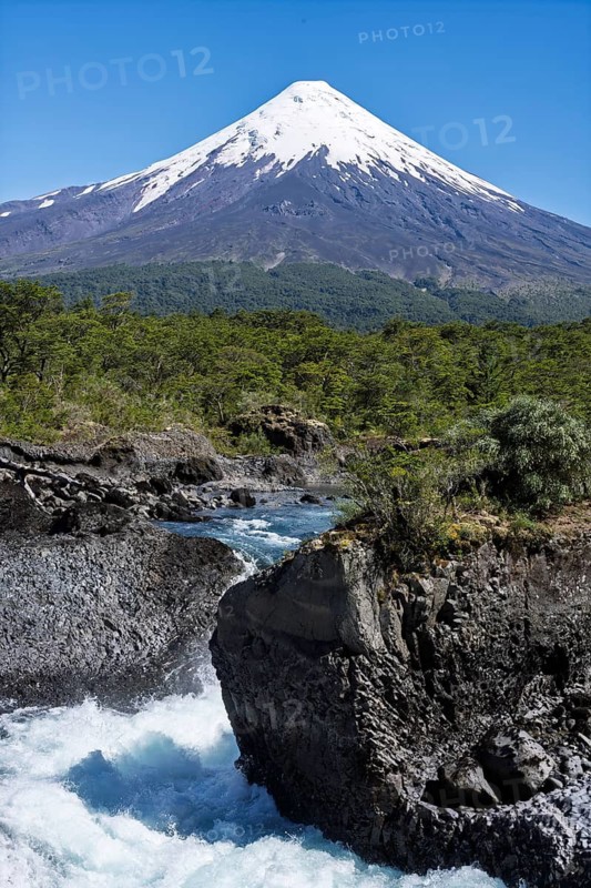 Snow-covered Osorno volcano with offshore Saltos del Petrohué, waterfalls over basalt rocks, dense forest in the middle ground, Vicente Pérez Rosales National Park, Los Lagos Region, Chile