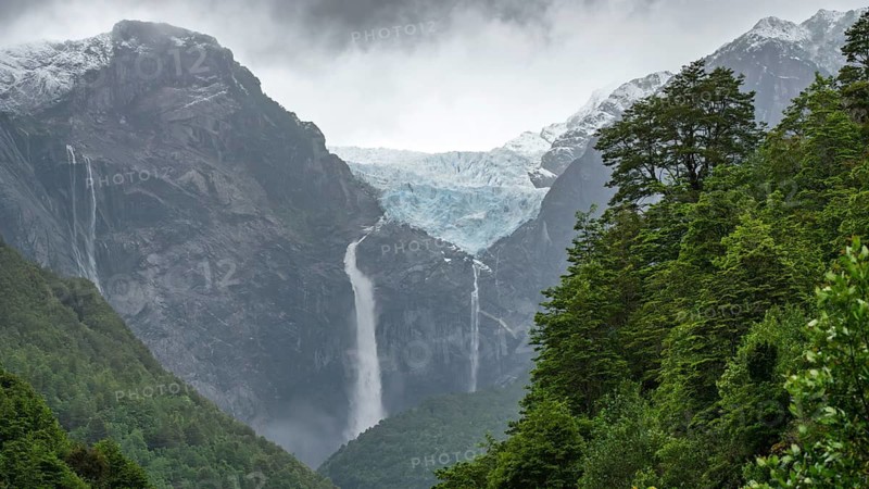 Ventisquero Colgante hanging glacier with cascading waterfall over steep rock face, surrounded by snow-capped mountain peaks and subpolar rainforest, Queulat National Park, Aysén region, Chile