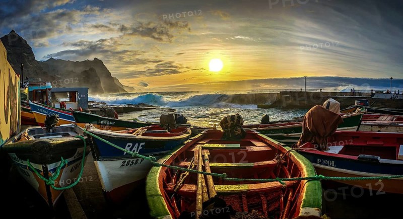 Colorful fishing boats on the shore with dramatic sunset in the background, waves making waves across the pier, romantic harbor scene, Ponta do Sol, Santo Antao, Cabo Verde, Cape Verde, Cape Verde